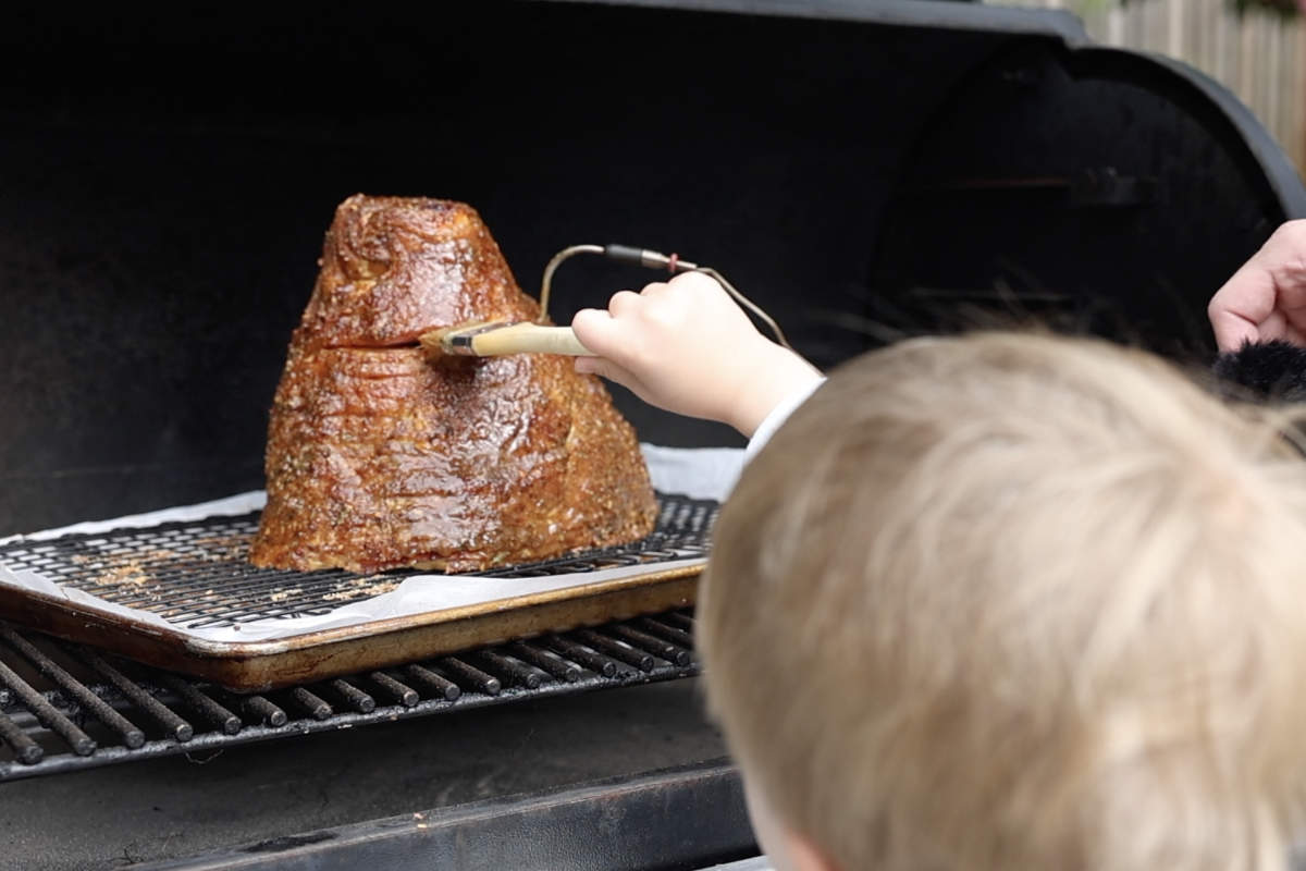 Brushing glaze on the ham while it is on the Traeger.