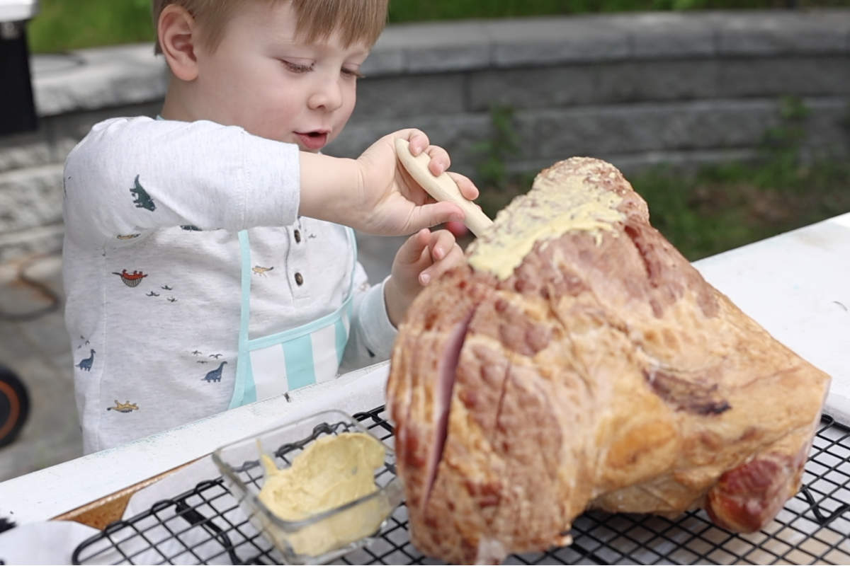 Brushing the ham with mustard.
