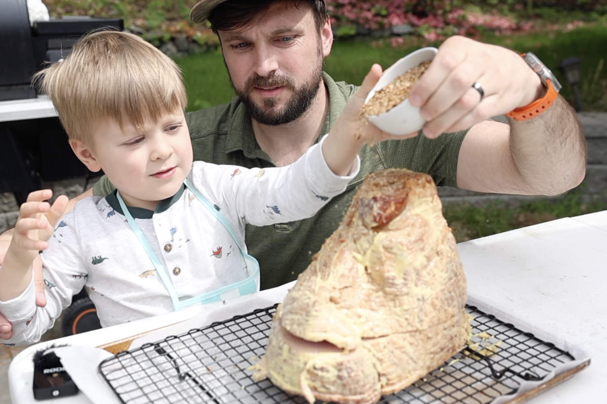 Seasoning the mustard coated spiral cut ham.
