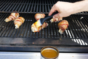 Brushing stuffed chicken legs with a glaze.