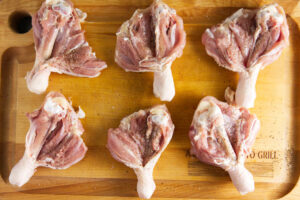 Butterflied chicken legs on a butcher block.