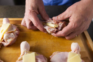 Stuffing a chicken leg with ham and cheese.