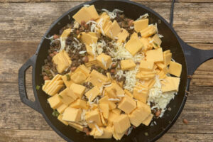 Diced American cheese, mozzarella cheese, and chili base ingredients in a large skillet.