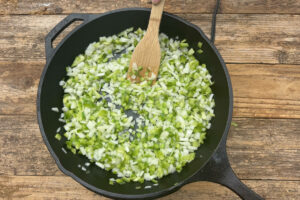 Sautéing onions, green pepper, and jalapeño peppers in a large skillet.