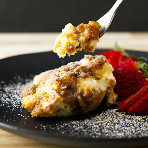 Taking a bite of French toast casserole, fork hovering over the plate.