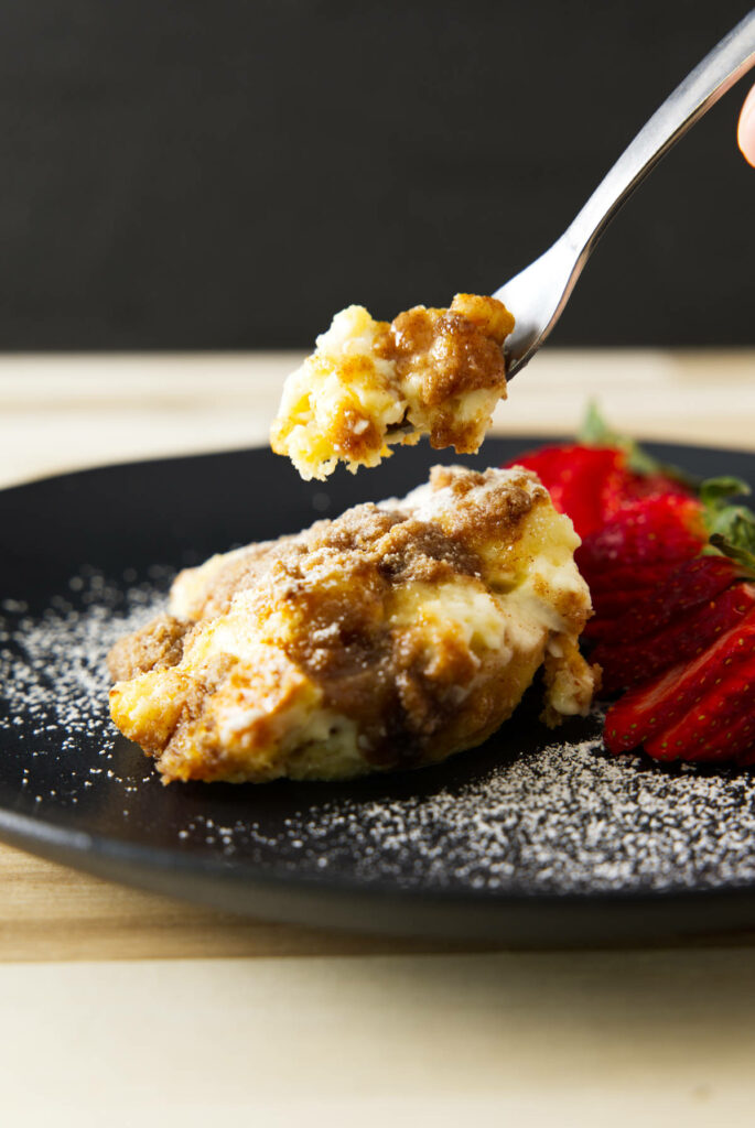Taking a bite of French toast casserole, fork hovering over the plate.