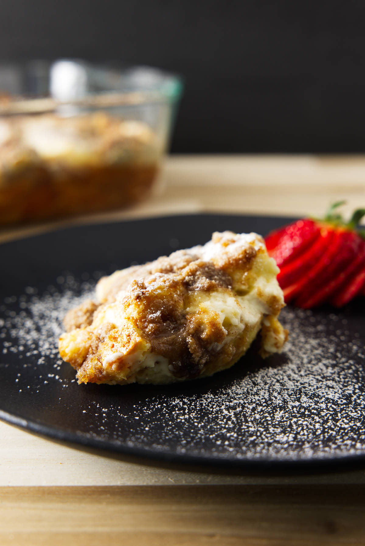 Scoop of French toast casserole plated and dusted with powdered sugar.