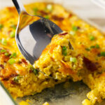 Large spoon full of corn casserole from baking dish.