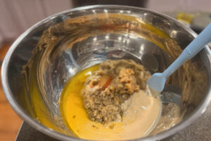 Large metal mixing bowl filled with chopped eggplant, tahini, and olive oil.