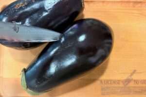 Piercing skin of eggplant with a knife.