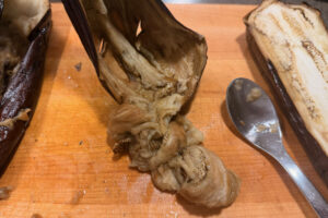 Scraping flesh from roasted eggplant.