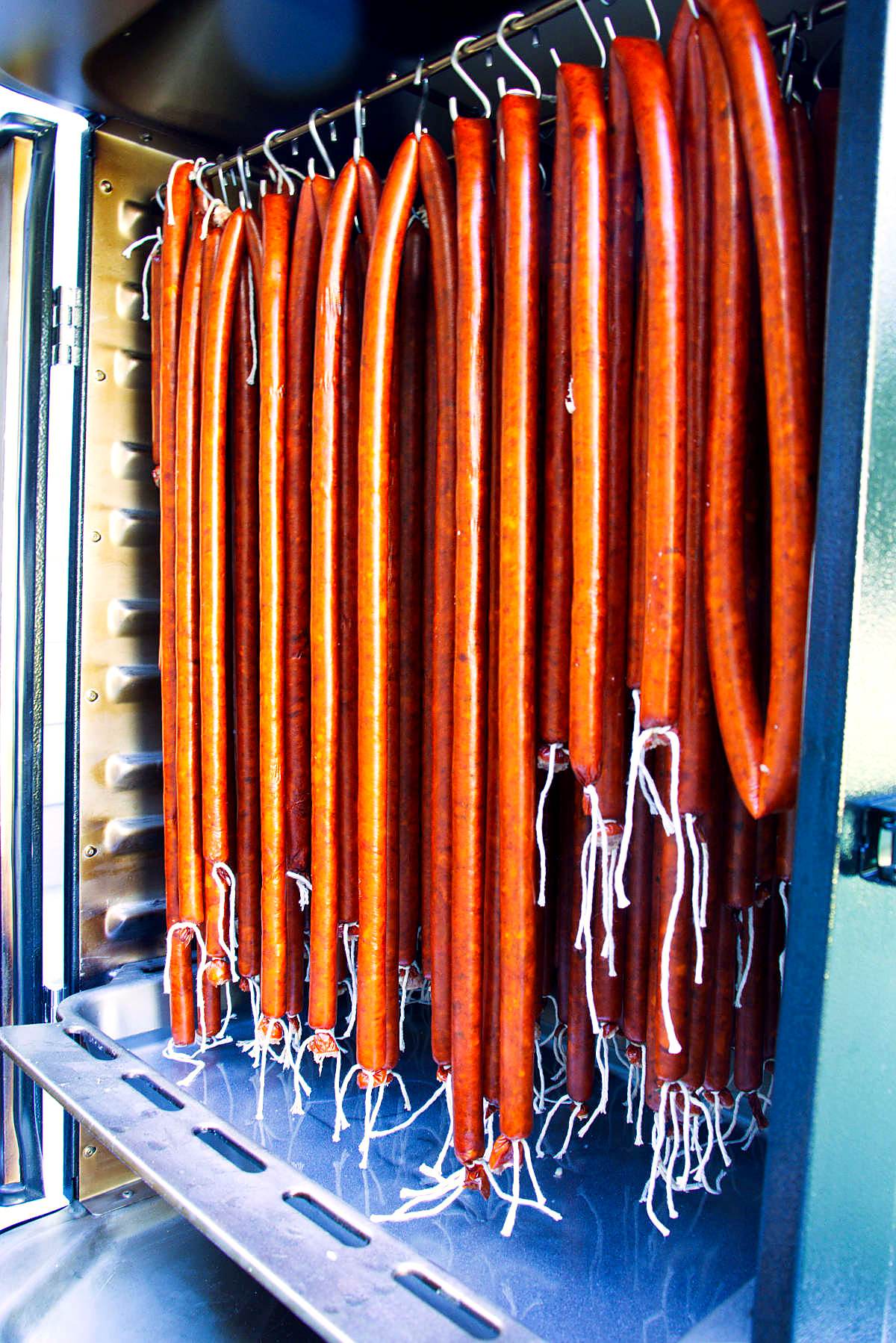 Hanging snack sticks in a tall vertical smoker.