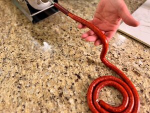 Stuffing snack sticks and coiling them on the counter.