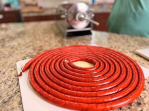 Smoked venison snack sticks stuffed and coiled on cutting counter.