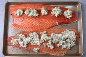 Dollops of compound butter on top of two fillets of salmon.