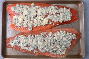 Spreading compound butter on top of two fillets of salmon.
