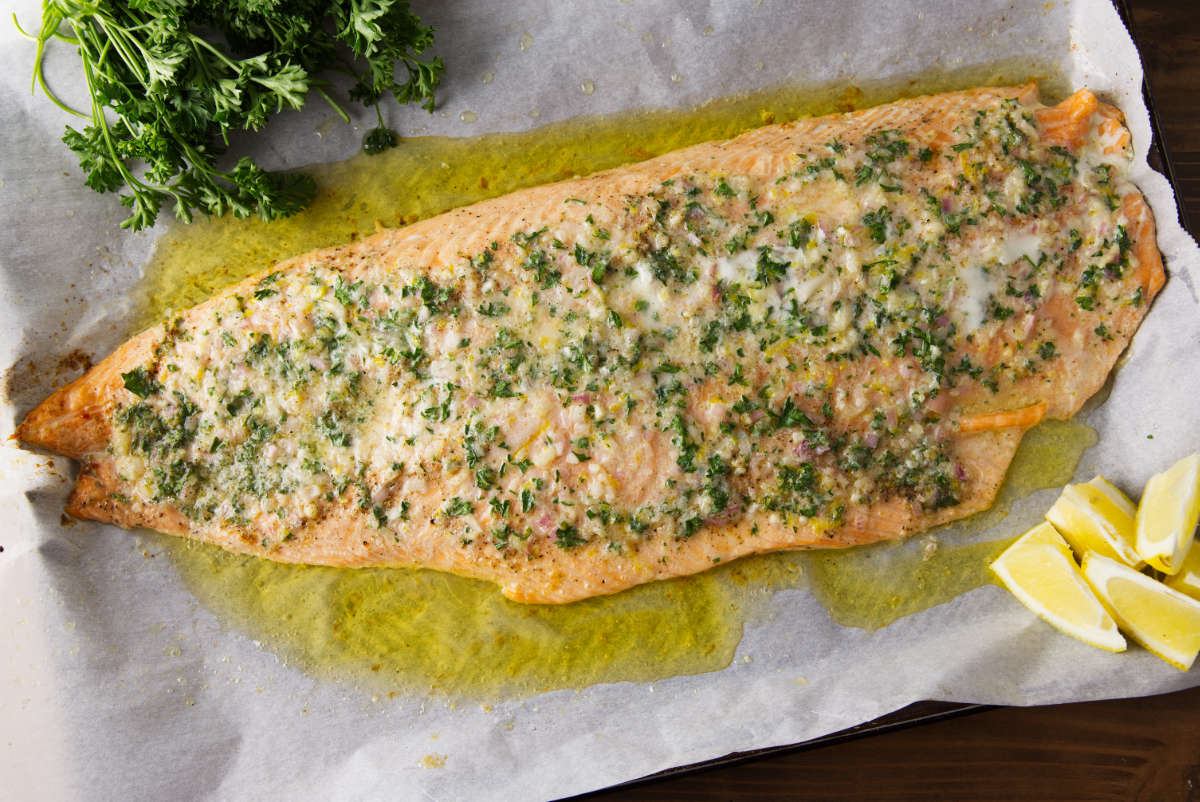 Pellet grill salmon coated in compound butter resting on parchment paper.