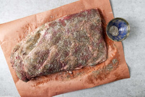 Covering a brisket with salt and pepper.