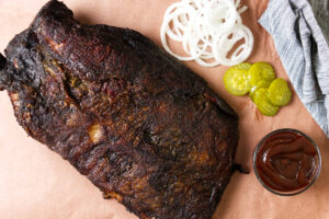 A smoked brisket on peach paper showing the dark bark.