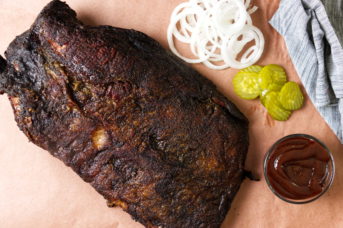 A smoked brisket on peach paper showing the dark bark.