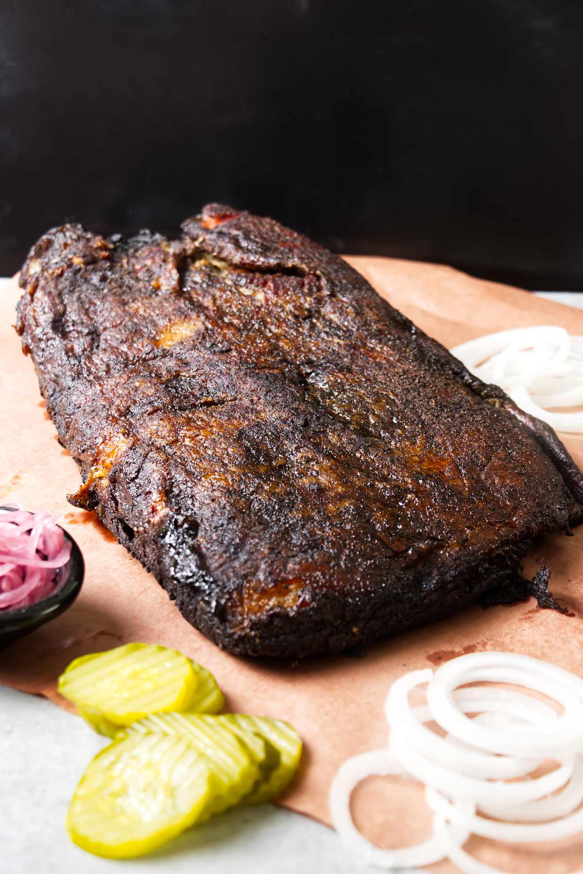 A smoked brisket on peach paper next to pickled onion.