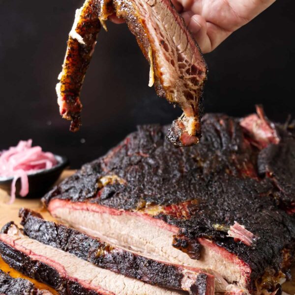 Hand holding a slice of smoked brisket.