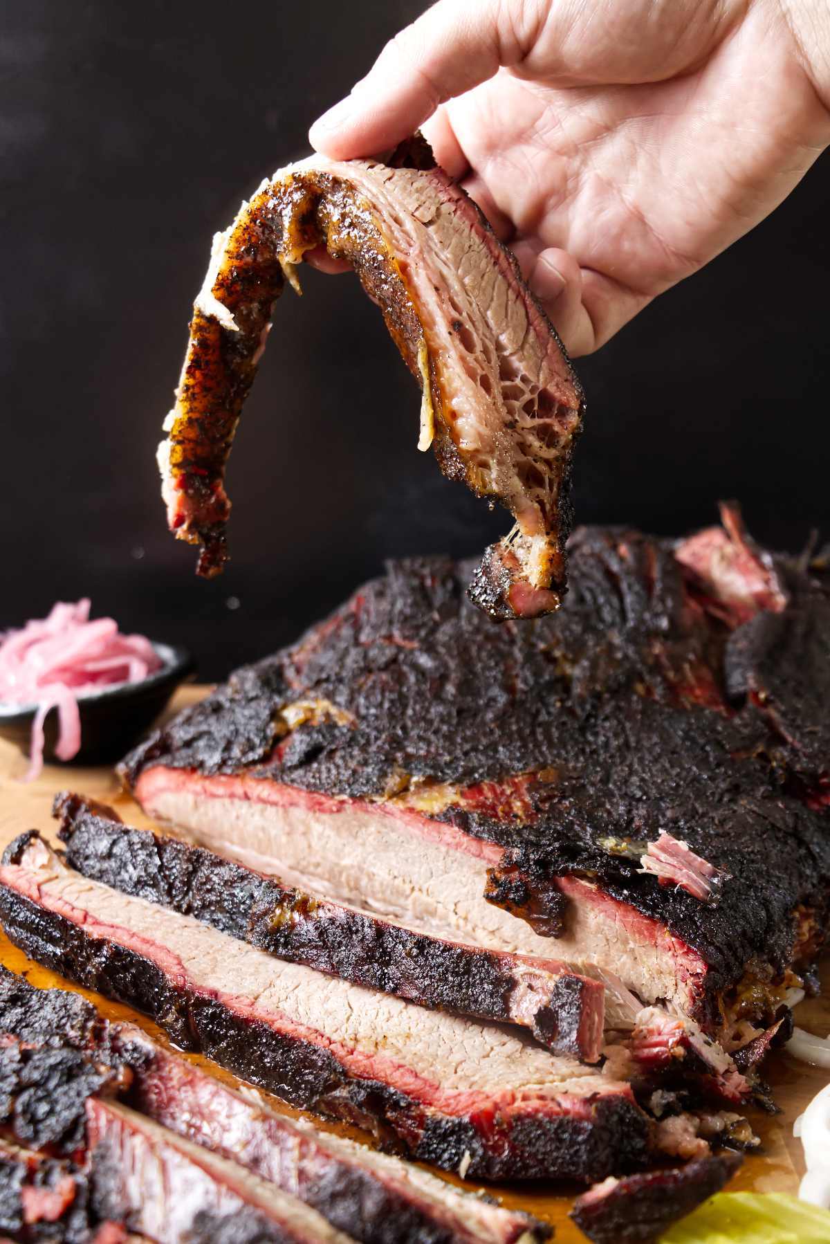 Hand holding a slice of smoked brisket.