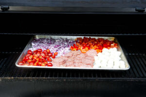 Smoking ingredients on a traeger grill to make Italian pasta salad.