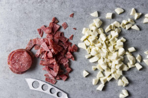 Slicing smoked mozzarella and salami for a pasta salad.