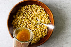 Tossing warm pasta with Italian dressing.