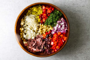 Adding the smoked ingredients to the salad bowl with the pasta.