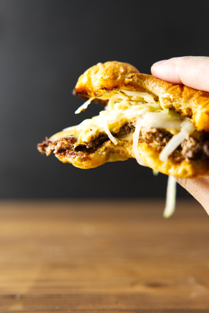 Bite taken out of burger being held by hand.
