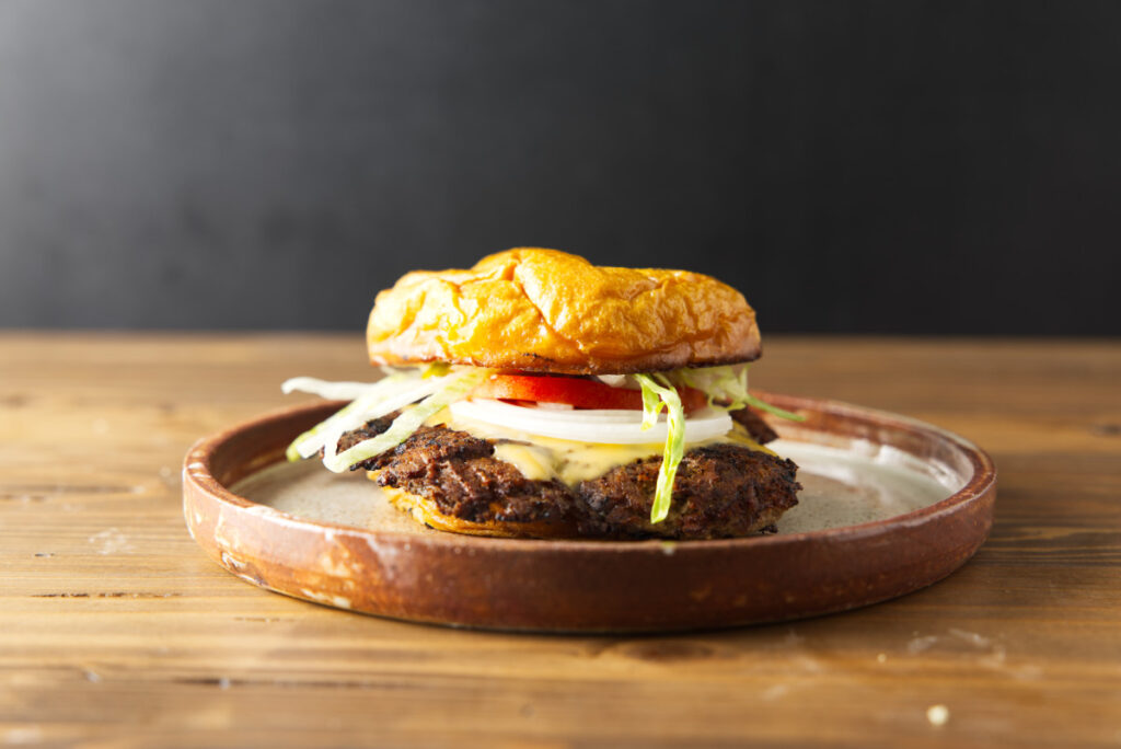 Blackstone smash burger plated on a brown ceramic plate and resting on a wood butcher block.