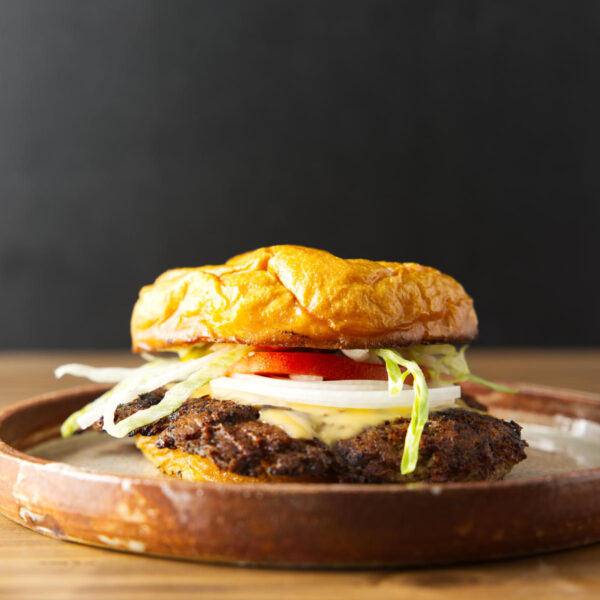 Blackstone smash burger loaded with toppings and smash burger sauce plated on a brown ceramic dish.