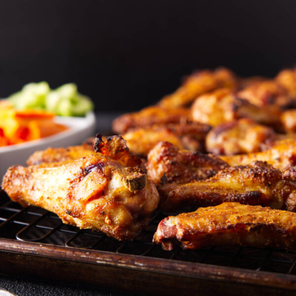 Smoked chicken wings arranged on a wire rack with celery and carrots.