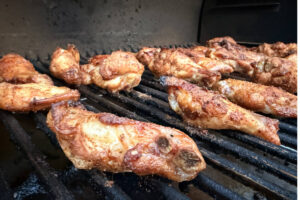Chicken wings smoking on the Traeger grill grates.