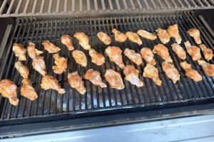 Seasoned chicken rings laying spread out on Traeger grill grates.