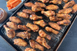 Chicken wings coming off a Traeger smoker on a wire rack over sheet pan.