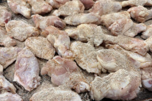 Tossing chicken wings in seasoning on a sheet pan.
