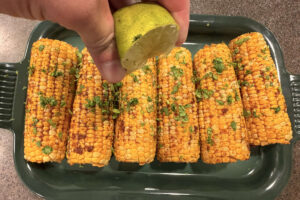 Finishing smoked corn on the cob with fresh lime juice.