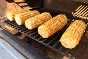 Corn on the cob smoking directly on the pellet grill grates.