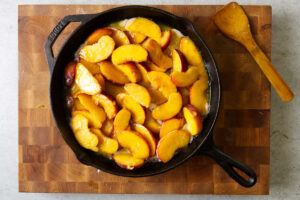 Adding sliced peaches to a skillet.