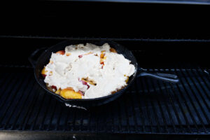 Placing a cast iron skillet on a pellet grill.