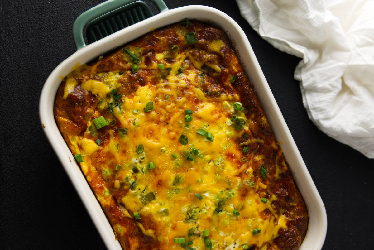 Overhead view of the baked breakfast casserole with a golden cheese topping and sliced green onions.