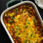 Green and white ceramic baking dish with Crescent roll breakfast casserole, topped with melted cheese and browned around the edges.